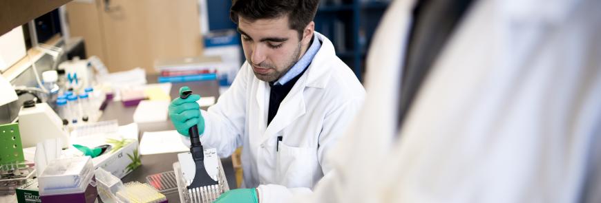 A man sits at a table pipetting.