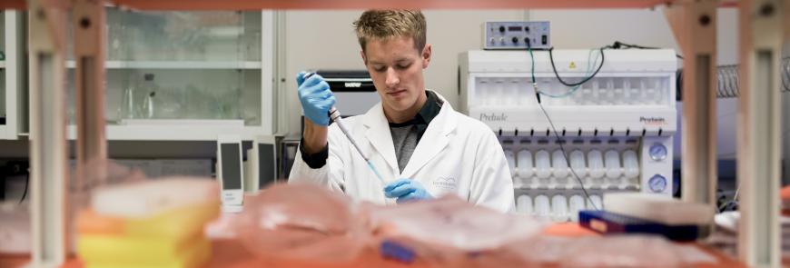 A man in a lab uses a pipette.