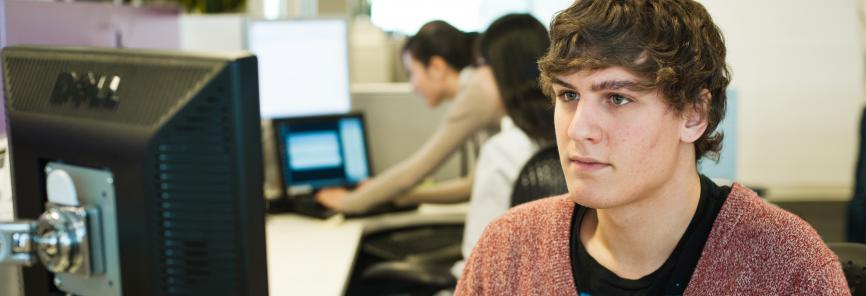 A student sits at a desktop computer.