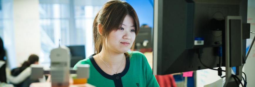 a woman sits at a desktop.