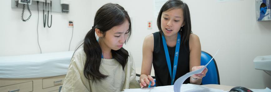 Two women sit at a table in a medical office.