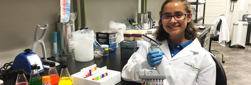 A woman sits at a table in a lab. 