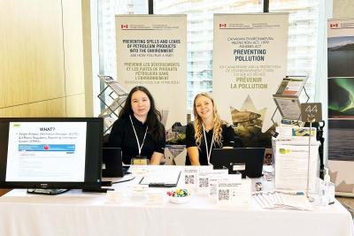 Two Science Co-op students sit at a booth about preventing pollution.