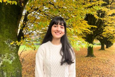 UBC Science Co-op Biology student Sarina Saffarian stands in front of autumn foliage.