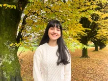 UBC Science Co-op Biology student Sarina Saffarian stands in front of autumn foliage.