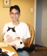 UBC Science Co-op Environmental Sciences student Eric Fang sits with his black and white cat Binoo.