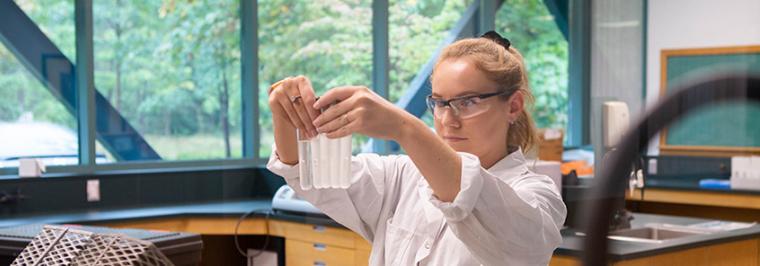 A woman holds up test tubes.