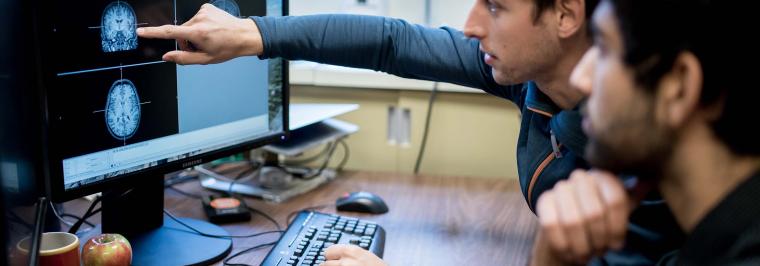 Two men sit at a computer.