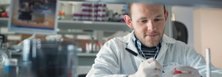 A man writes a label on a test tube.