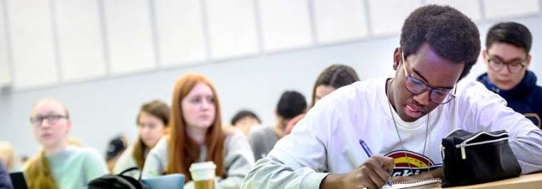 A student writes at a table.