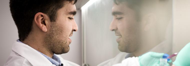A man looks at something in a fume hood.