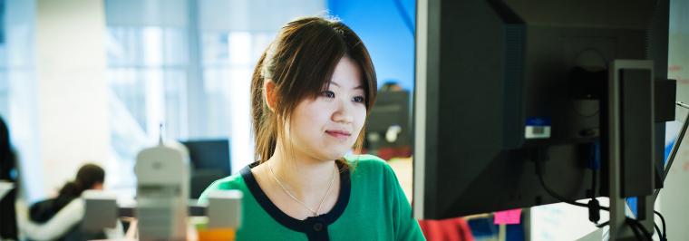 A woman sits at a computer.