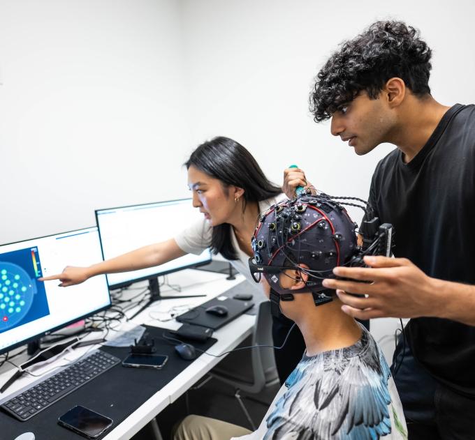 Three students look at a screen together.