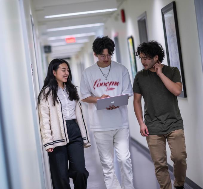 Three students walk down a hallway together.